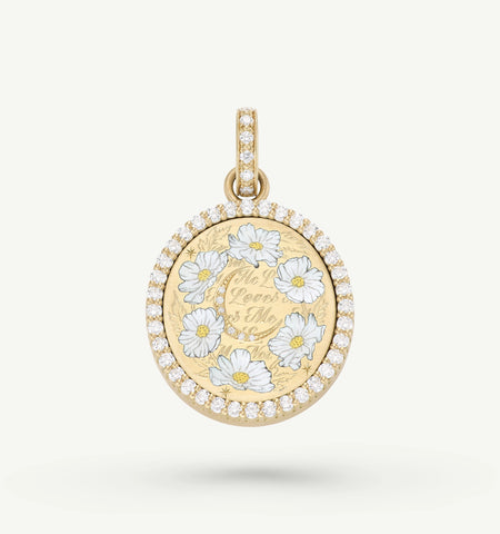 Gold pendant featuring white enamel flowers and a decorative engraving, framed by a circle of diamonds.