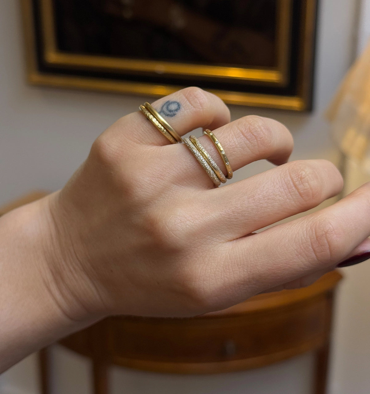 Woman wearing multiple gold rings on her hand in different textures and designs.