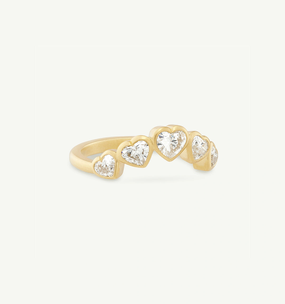 Gold ring featuring five heart-shaped diamonds set in a curved design.