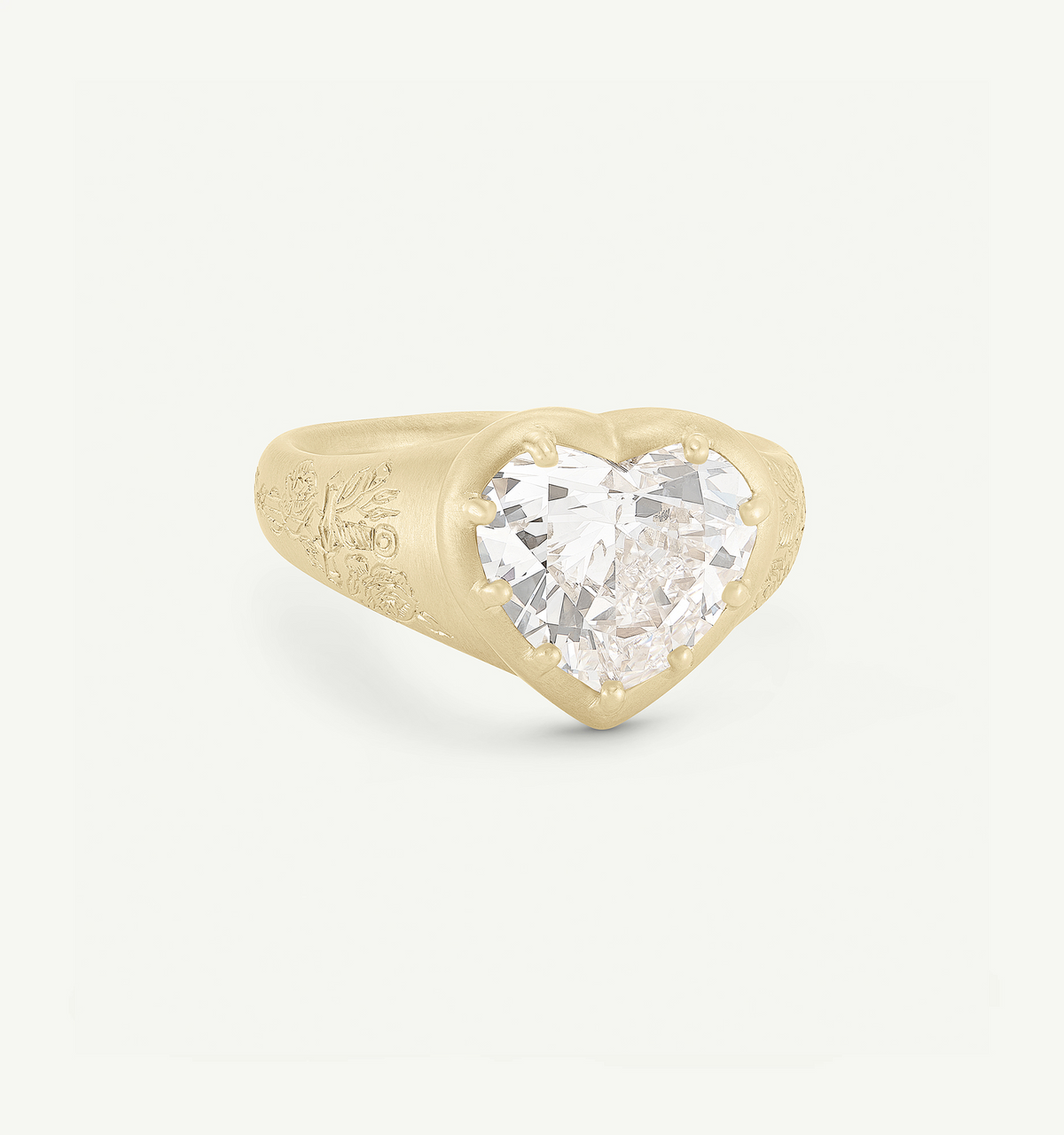Heart-shaped gold ring featuring a large round diamond and intricate engravings on the band.