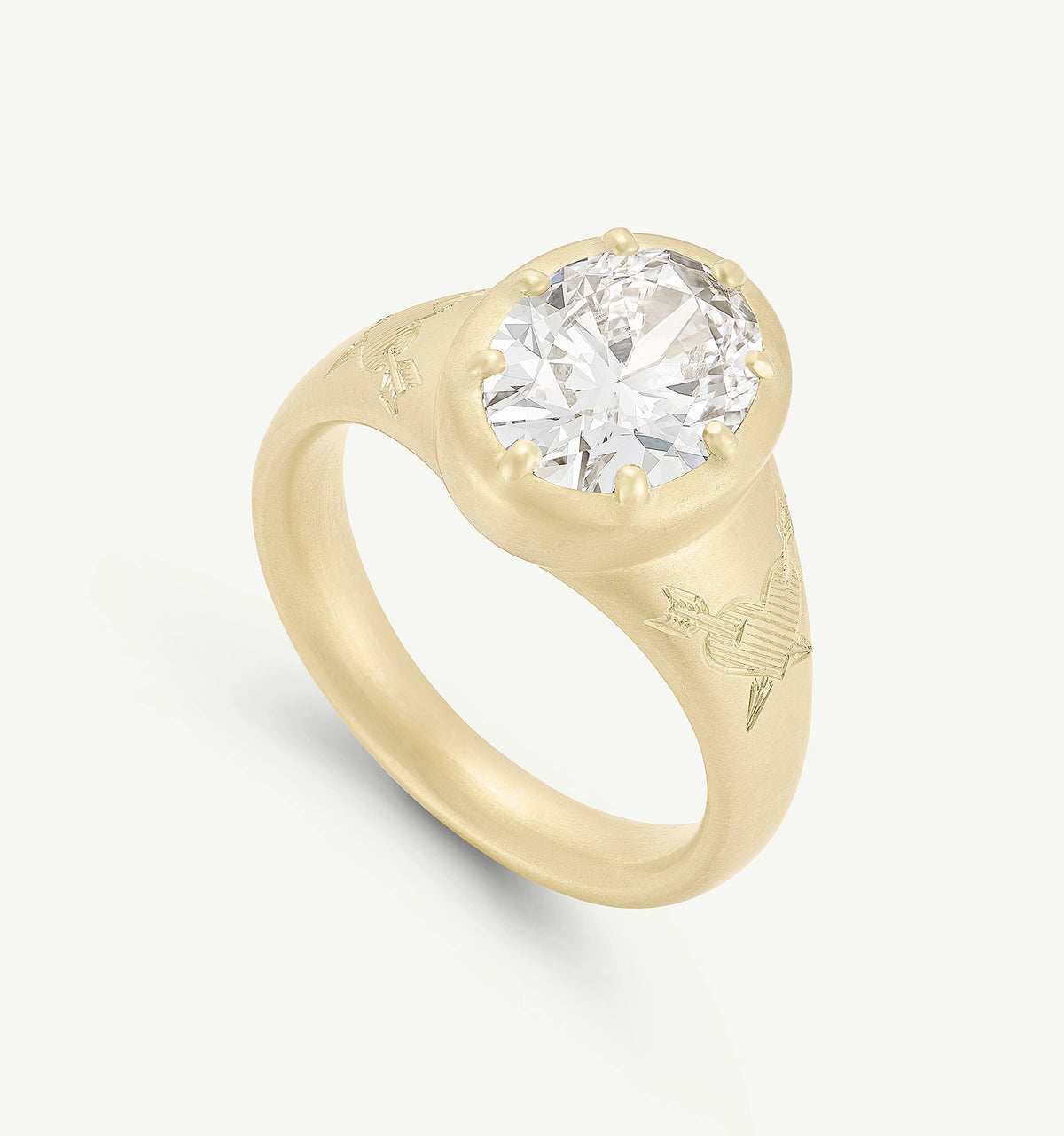Gold ring featuring a large round diamond, engraved with heart and arrow motifs on the band.