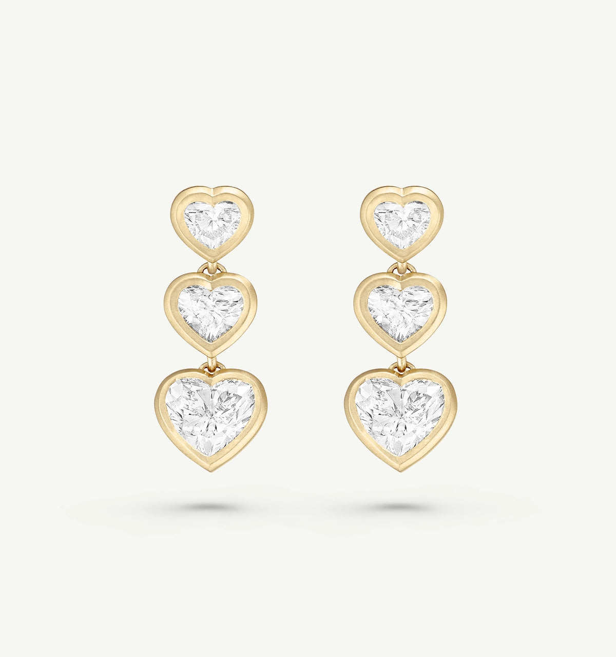 Gold earrings with three heart-shaped designs featuring clear diamonds.