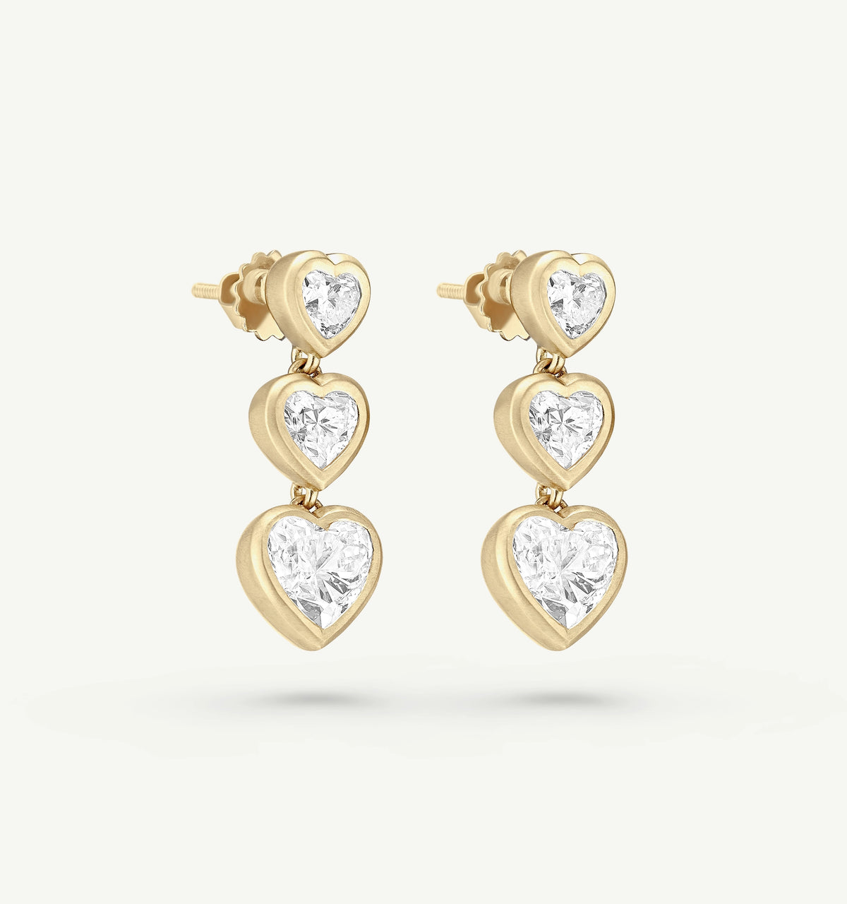 Gold earrings featuring three heart-shaped settings with clear diamonds.