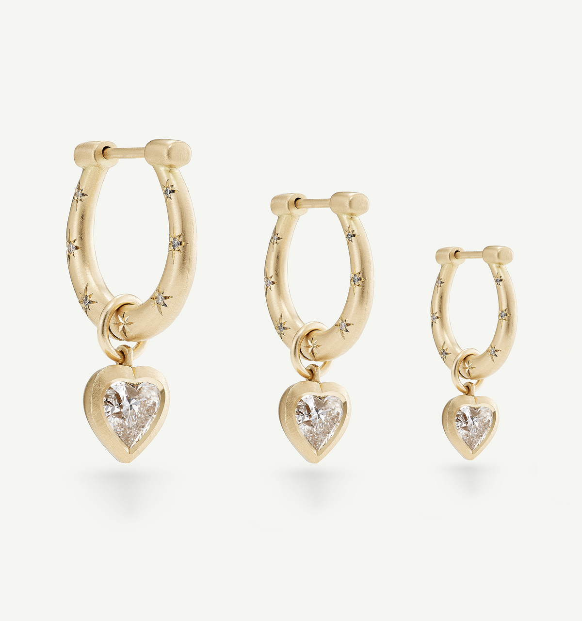 Gold hoop earrings featuring heart-shaped diamonds and star engravings in various sizes.