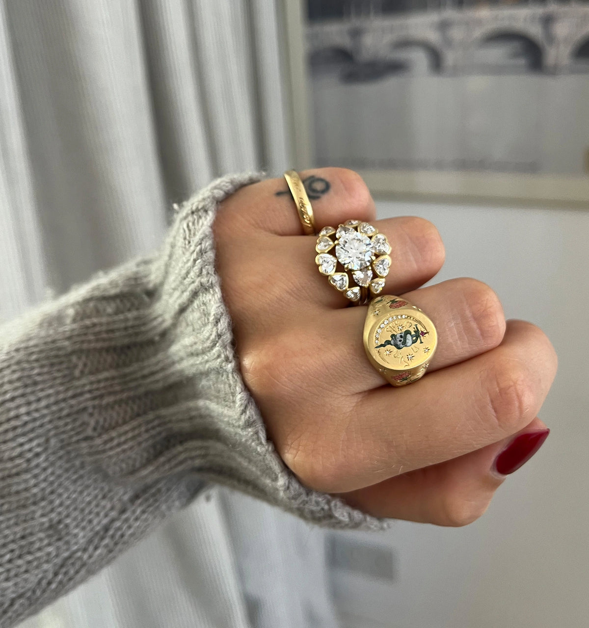Woman wearing three gold rings, including a gold ring with a flower-like design featuring diamonds.
