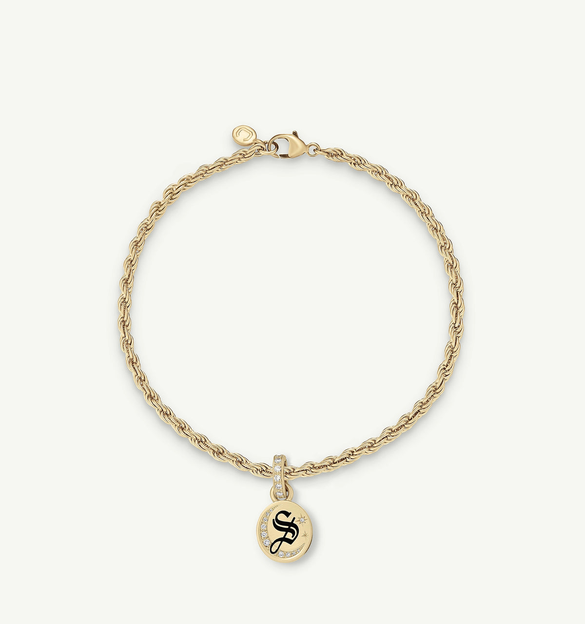 Gold bracelet featuring a twisted chain design and a circular pendant with a black logo and small diamonds.