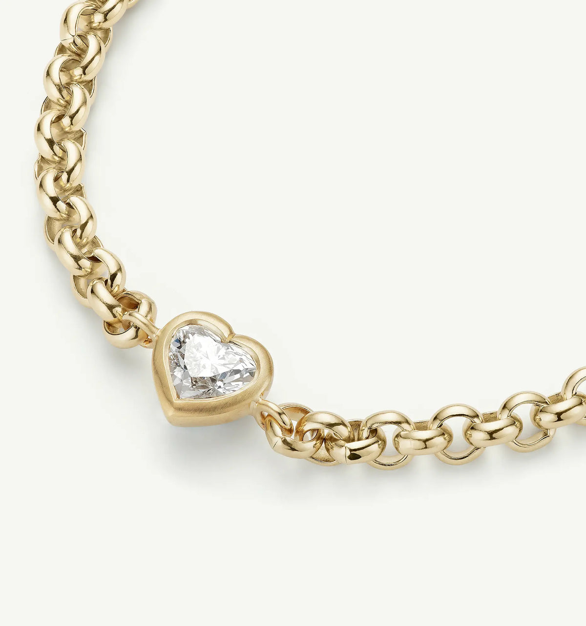 Close-up of a gold chain necklace with a heart-shaped diamond charm in a bezel setting.