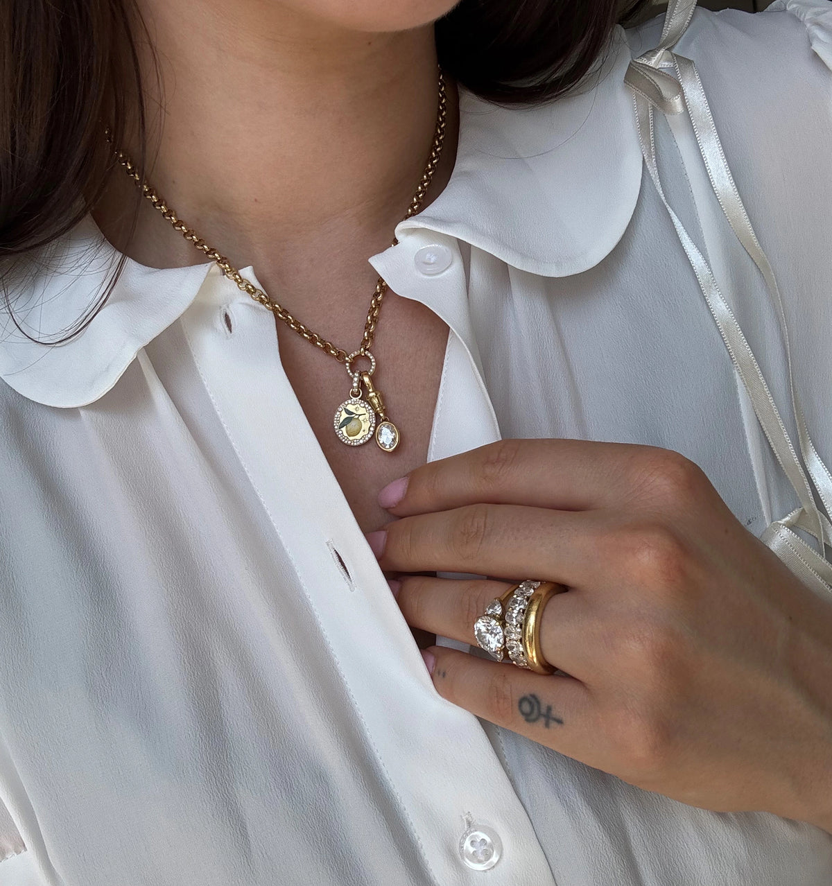 Woman wearing a gold chain necklace with a charm and a gold ring set featuring diamonds