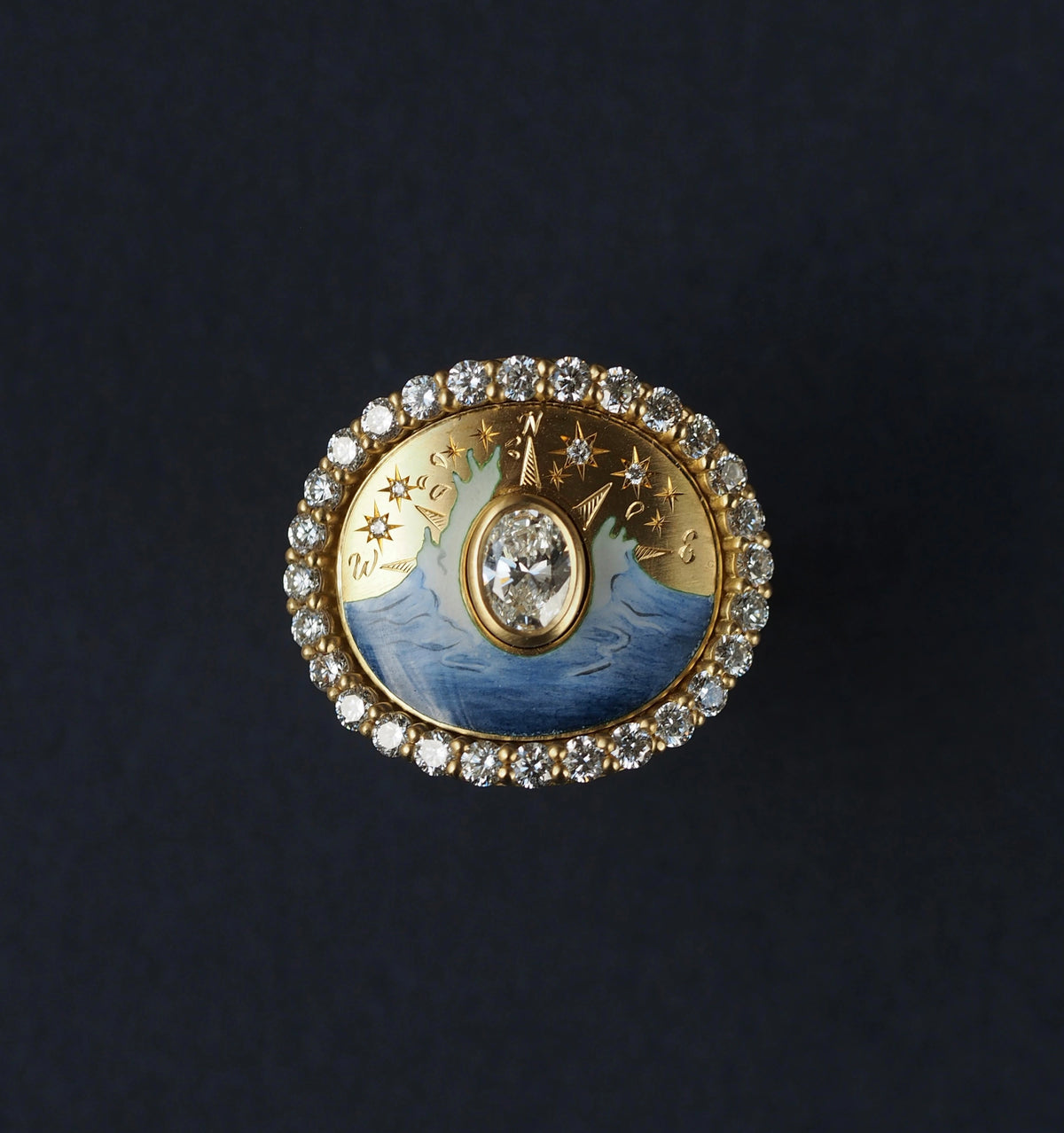 Gold ring featuring a central diamond surrounded by a blue enamel wave design and adorned with diamond accents.
