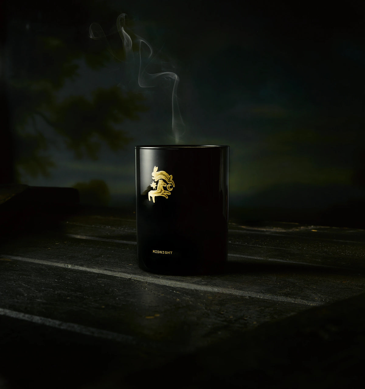 Gold candle holder featuring a unicorn design, with wisps of smoke rising against a dark background.