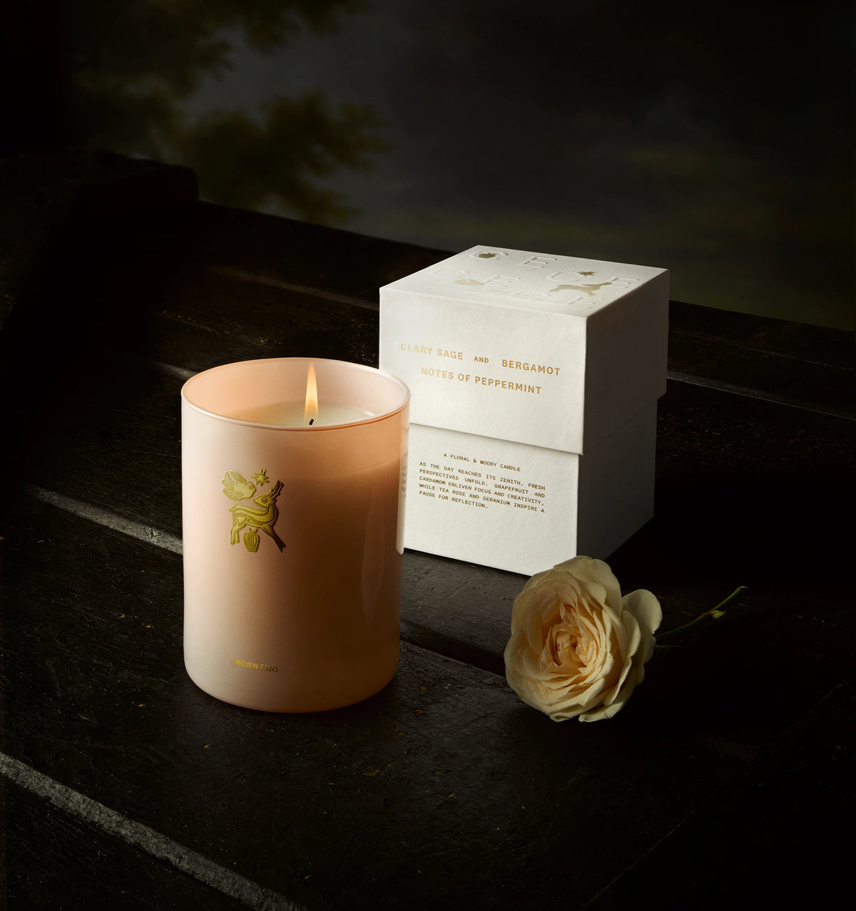 Woman wearing a gold ring next to a pink candle and a white rose on a dark wooden surface.