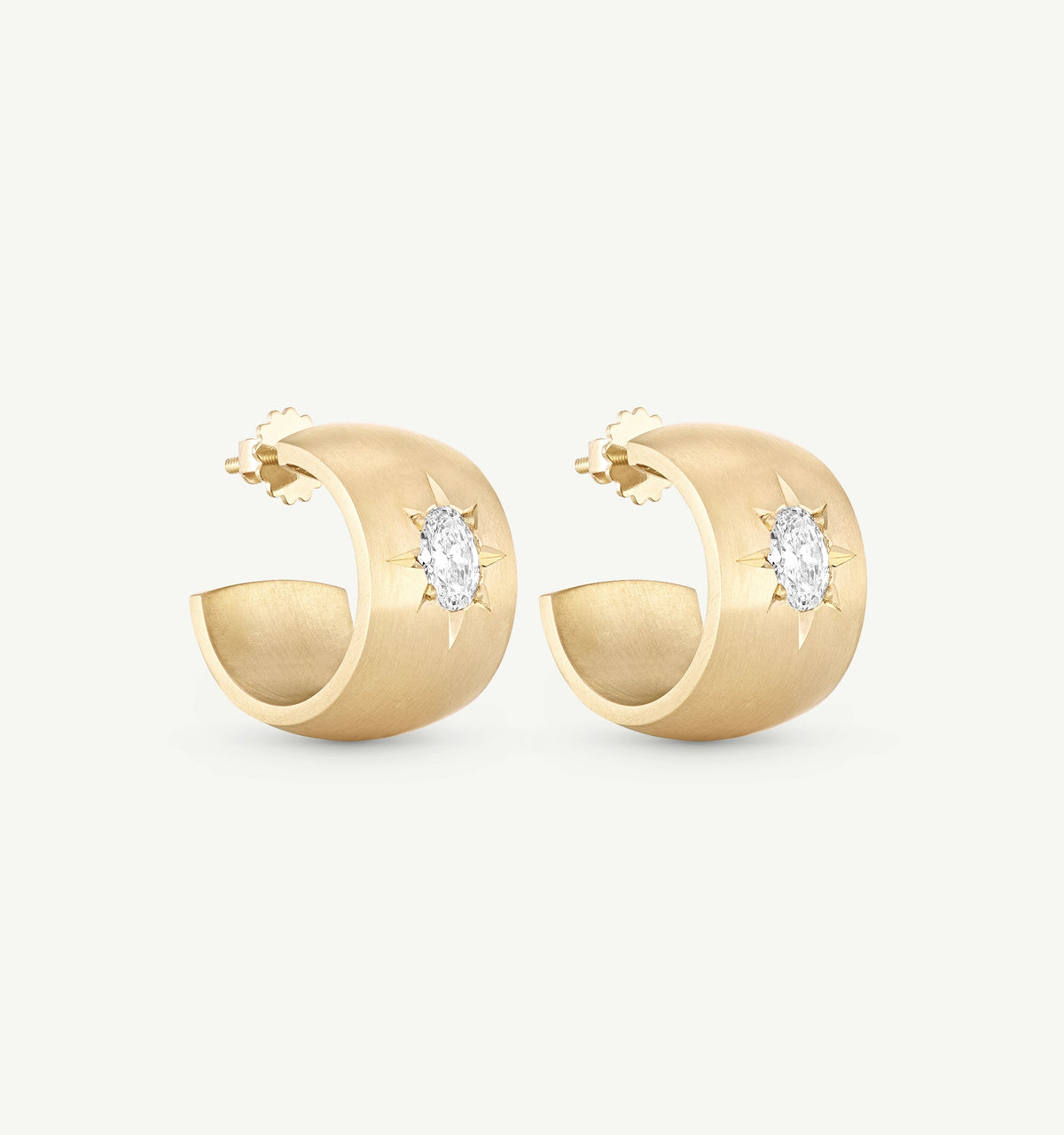Gold hoop earrings featuring an oval diamond in a sunburst setting.