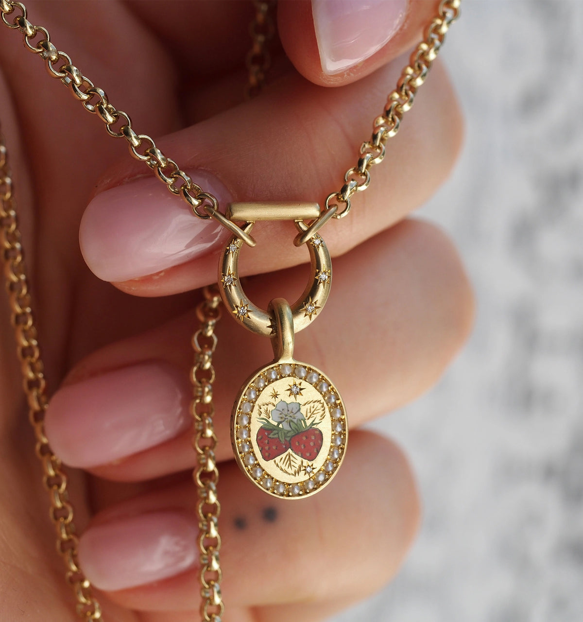 Gold pendant necklace featuring a hand-painted strawberry design and decorative gold star accents.