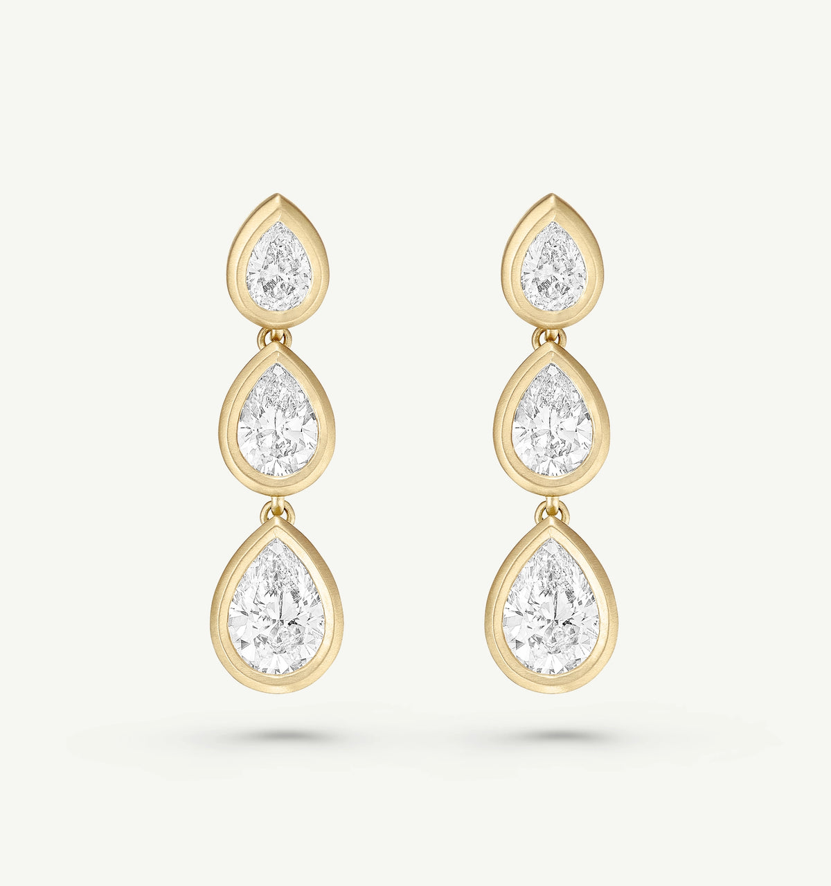 Gold earrings with three drop-shaped diamonds in a cascading design.