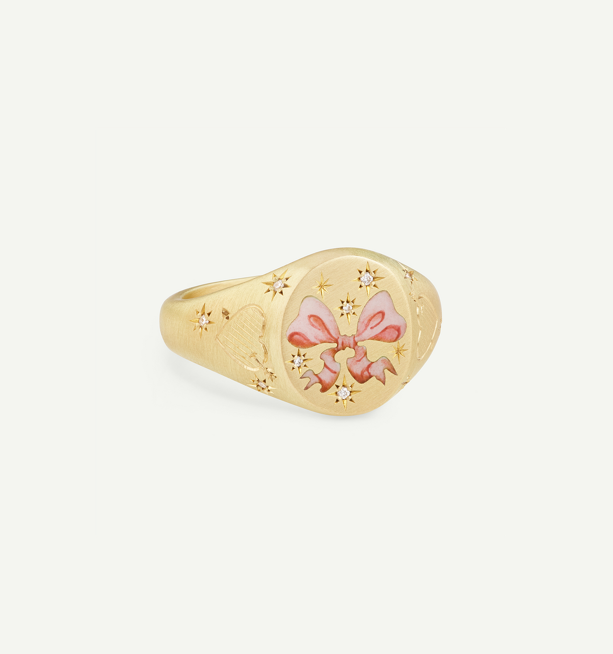 Gold ring featuring a pink enamel bow design with star motifs and engraved hearts.