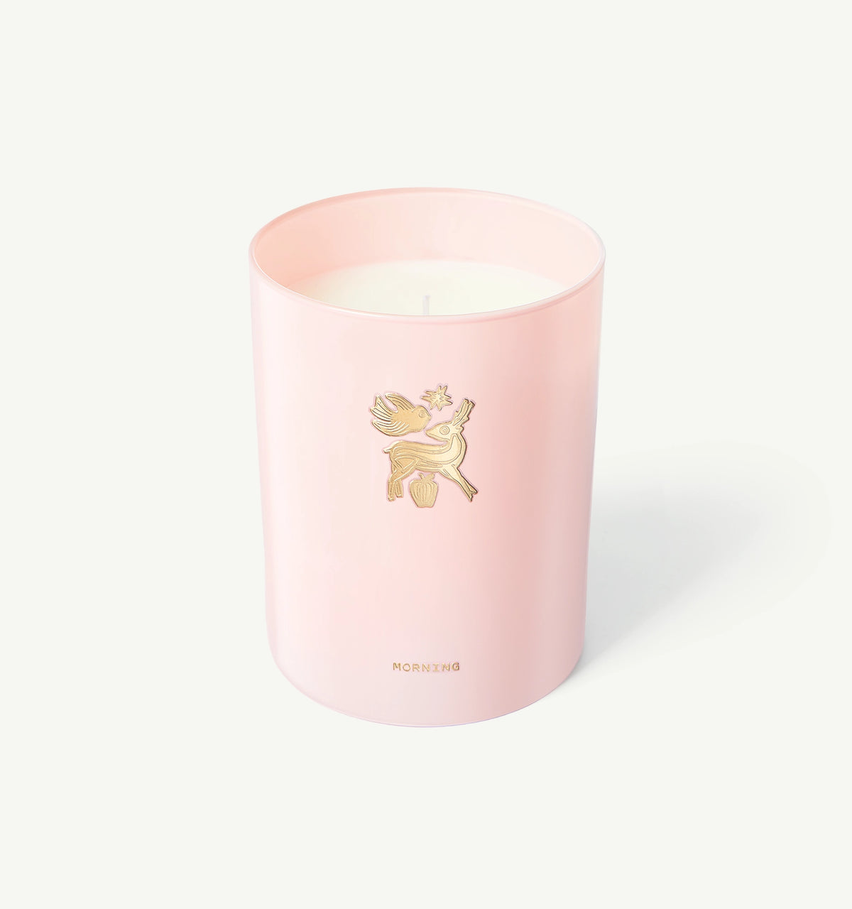 Woman wearing a gold ring on her finger beside a pink candle with a decorative gold motif.