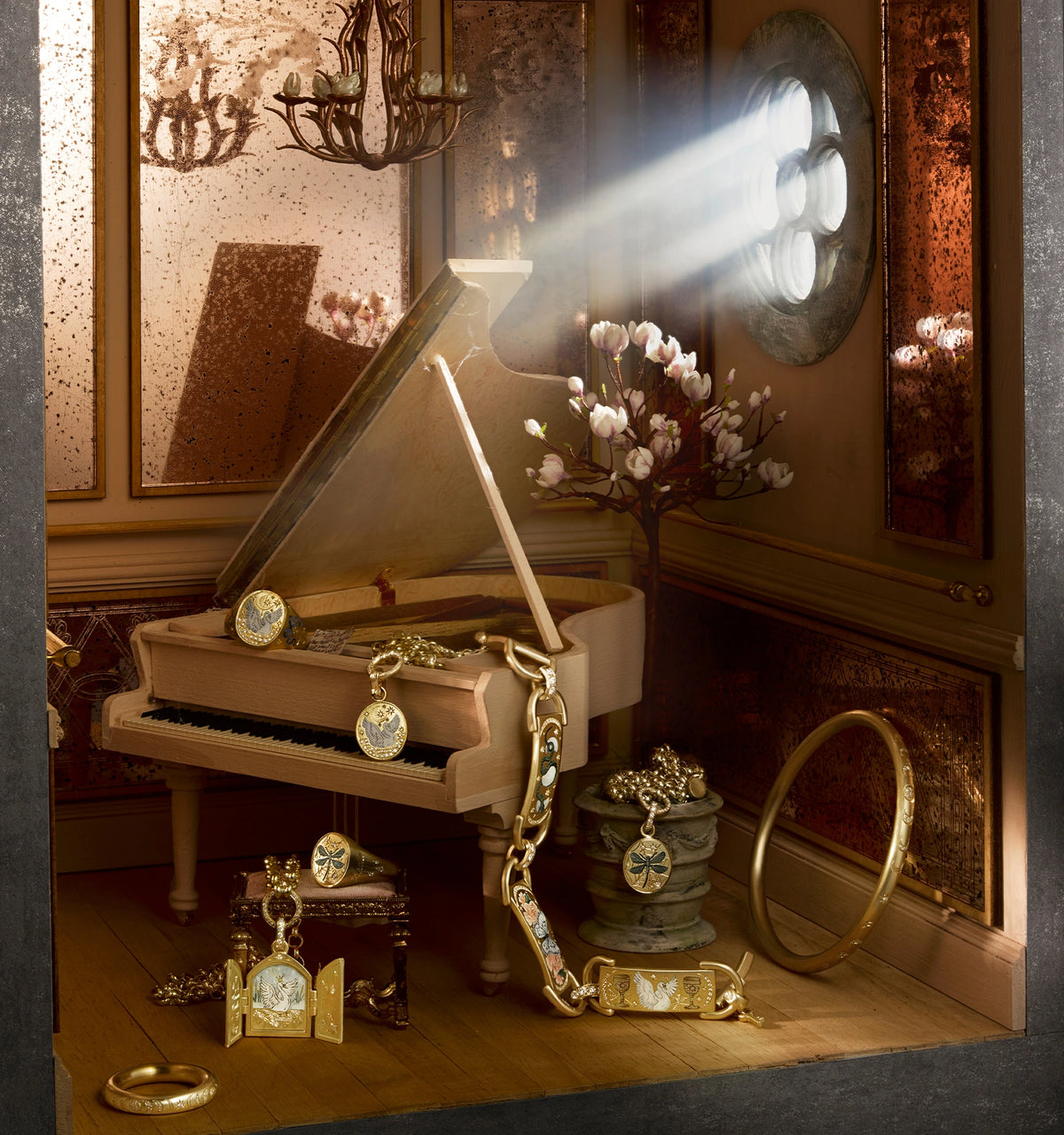 Gold jewellery displayed on a grand piano, including a ring, necklaces, and a bracelet, with floral accents and decorative details.