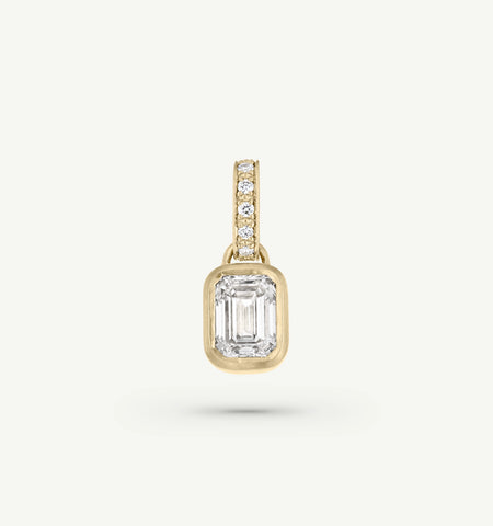 Gold pendant featuring an emerald-cut stone and round diamonds on the bail.
