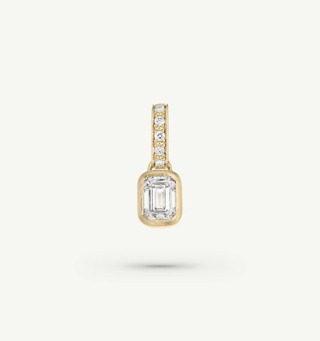 Gold pendant featuring an emerald-cut diamond and round diamonds in the bail.