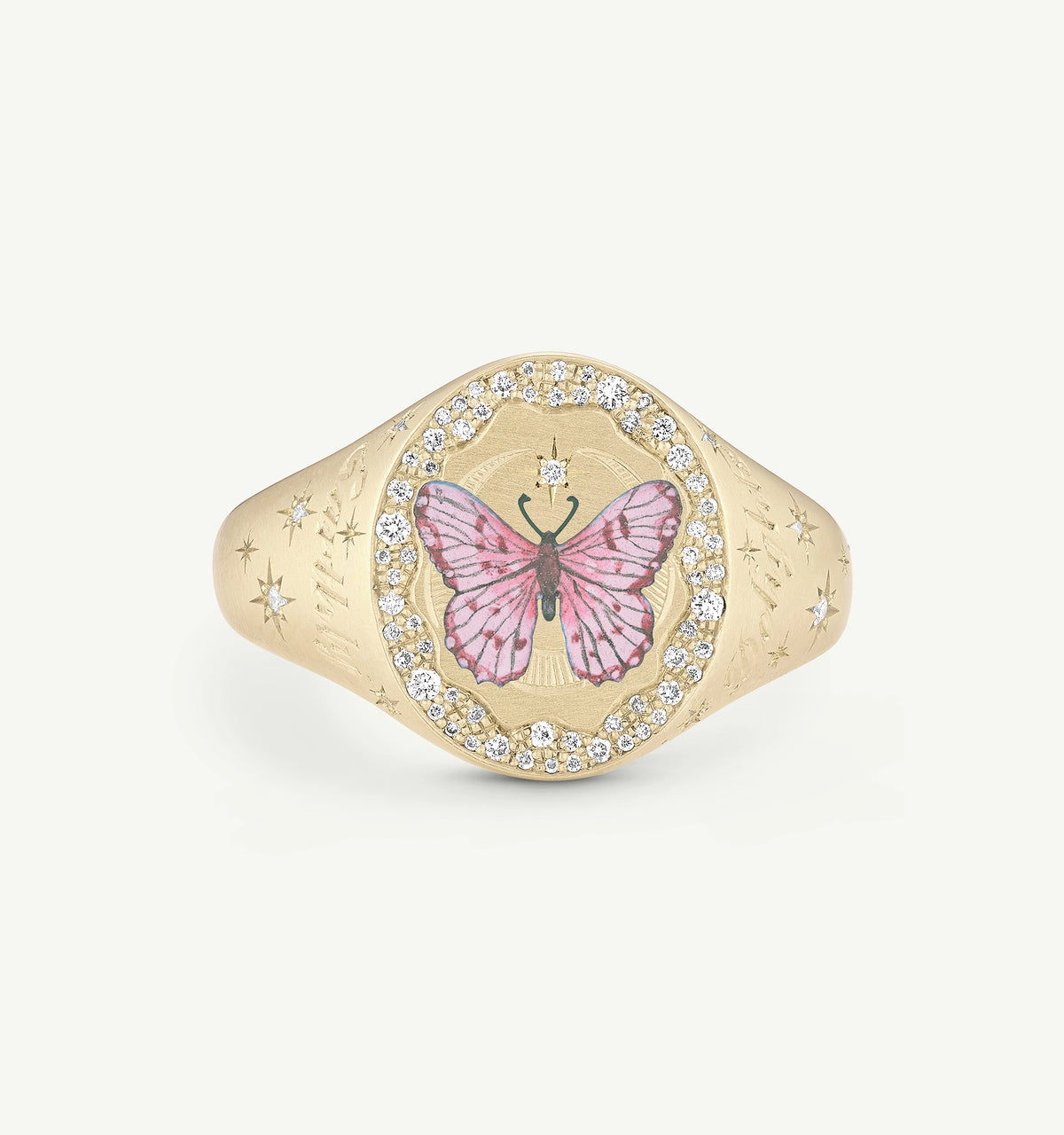 Gold ring featuring a pink butterfly design and surrounded by diamonds on a textured background.
