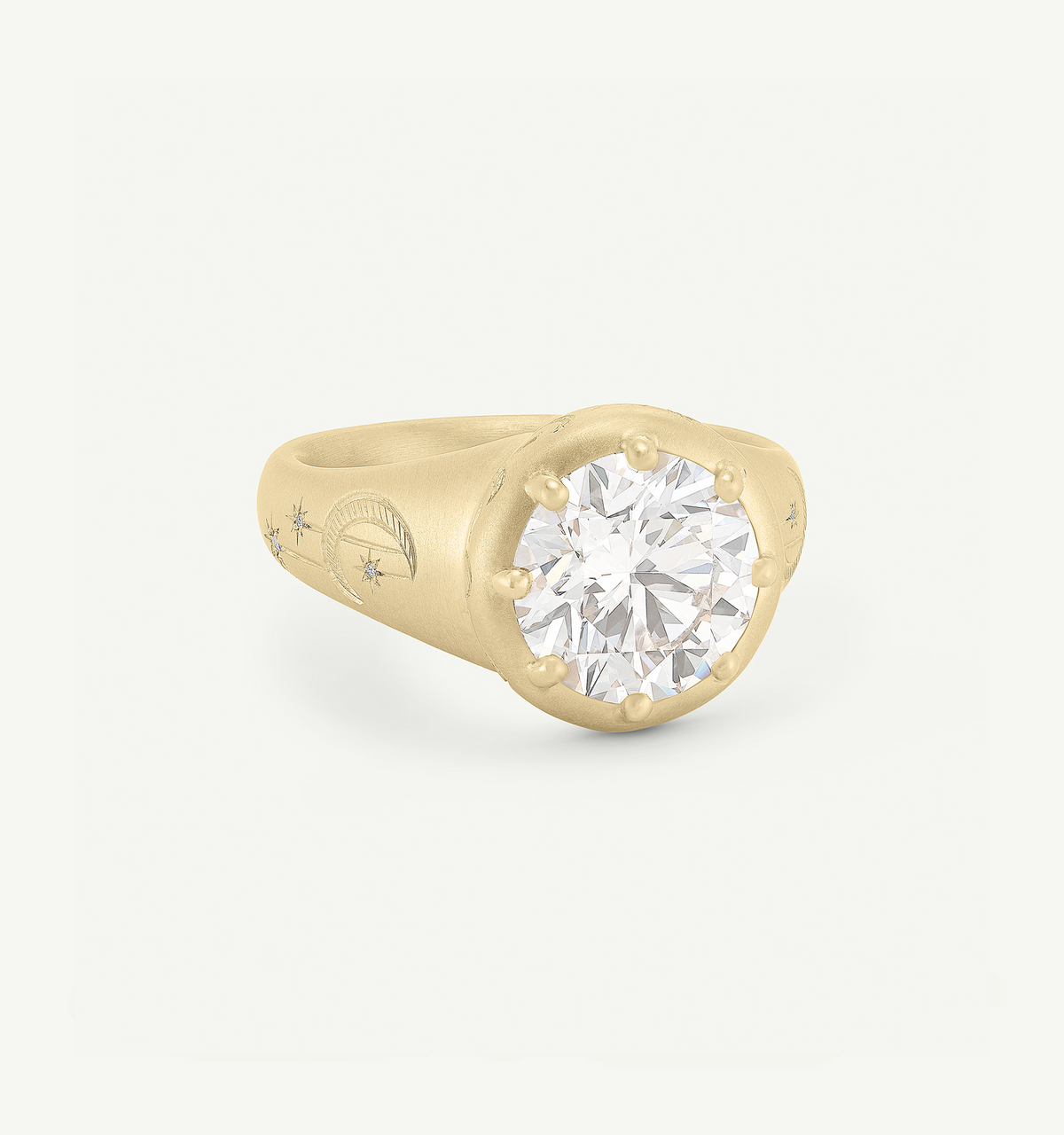 Gold ring featuring a round clear diamond, with engraved celestial motifs on the band.