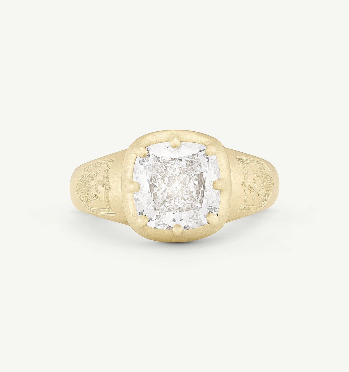 Gold ring featuring an engraved design and a clear diamond centrepiece.