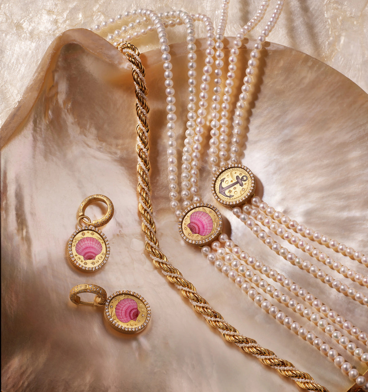 Gold earrings featuring pink shells and a gold twist bracelet alongside multiple strands of pearl necklaces on a shell surface.