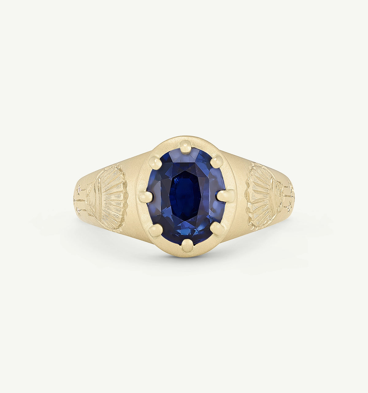 Gold ring featuring an oval sapphire centre stone with engraved details on the band.