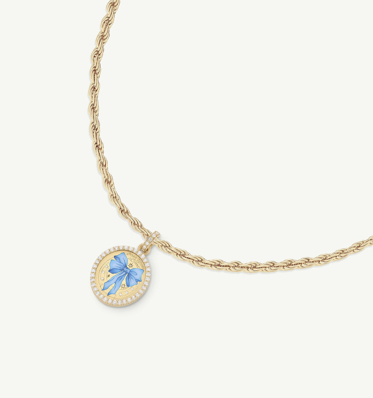 Gold necklace featuring a round pendant with a blue bow motif in enamel and a halo of gold detailing.