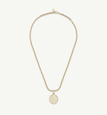 Gold pendant necklace featuring an ornate round pendant with intricate designs and a twisted chain.