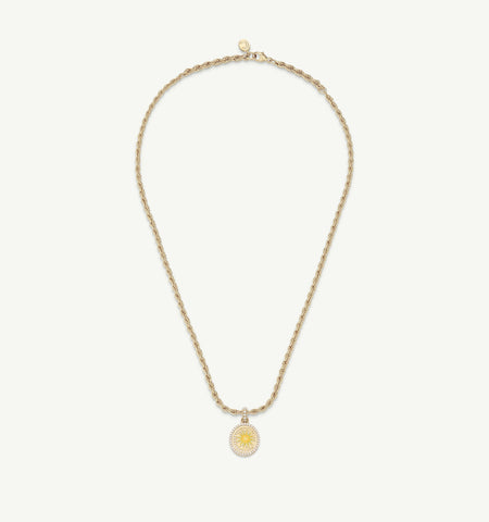Gold necklace featuring a round pendant with a sun motif and intricate detailing.