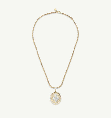Gold pendant necklace featuring a round charm with engraved design, set on a twisted gold chain.