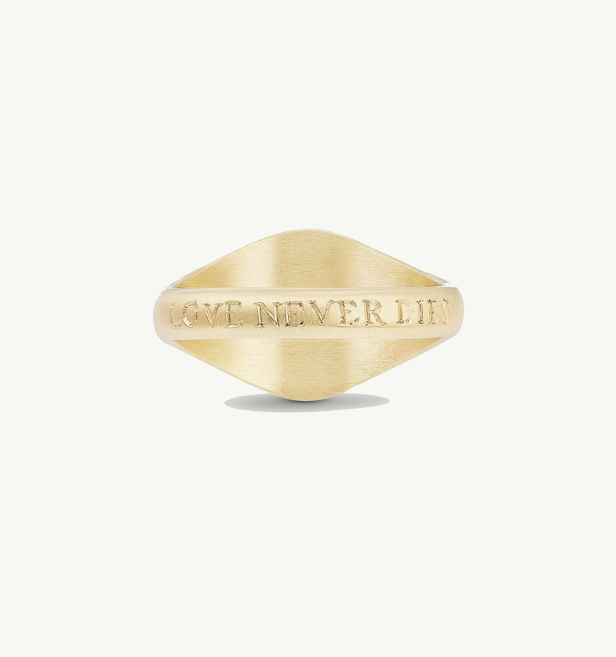 Gold ring with engraved text reading "LOVE NEVER DIES" on a light background.