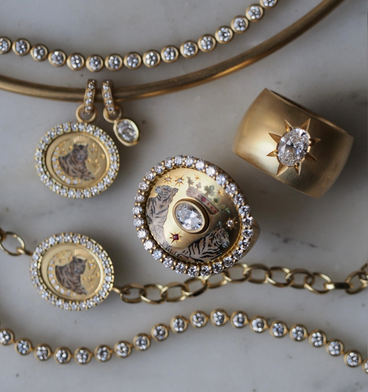 Gold jewellery arrangement featuring a ring with tiger design and white diamonds, paired with matching earrings and a chain.