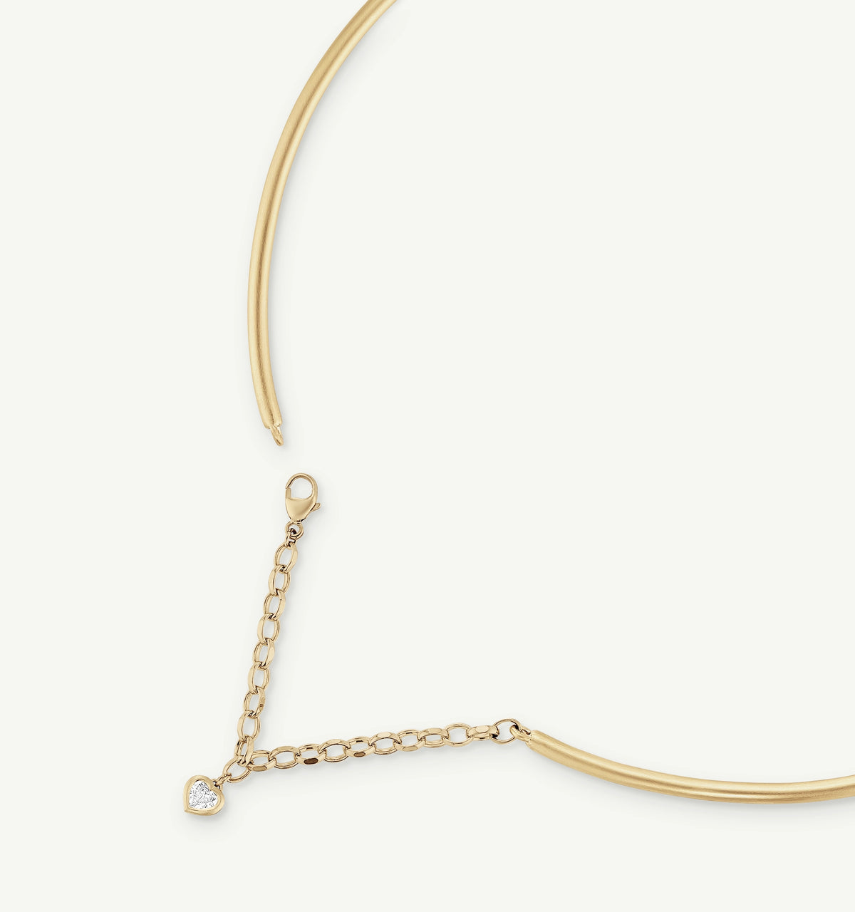Gold necklace featuring a heart pendant with a diamond accent, shown on a neutral background.