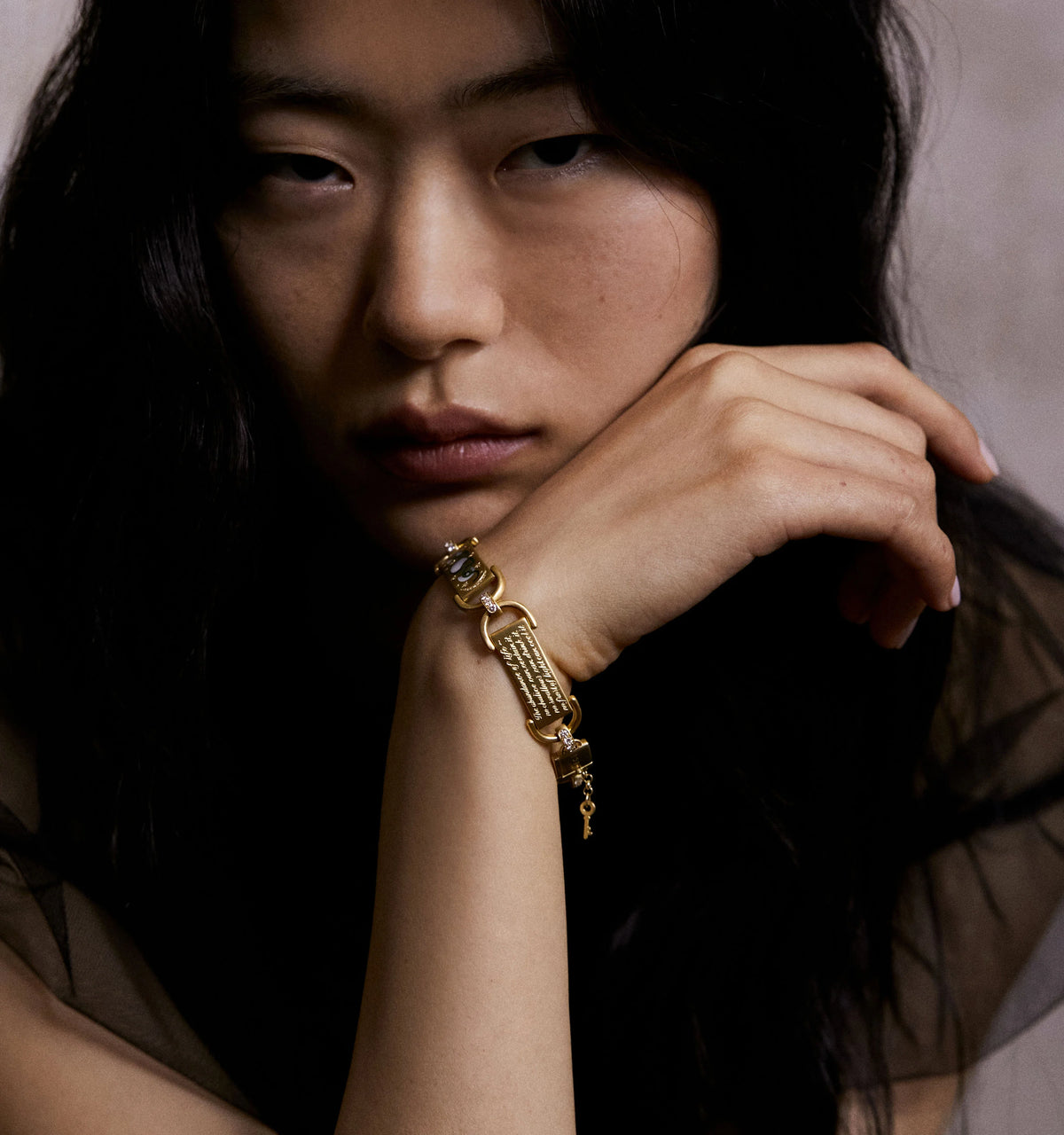 Woman wearing a gold bracelet with engraved details and a blue stone accent.