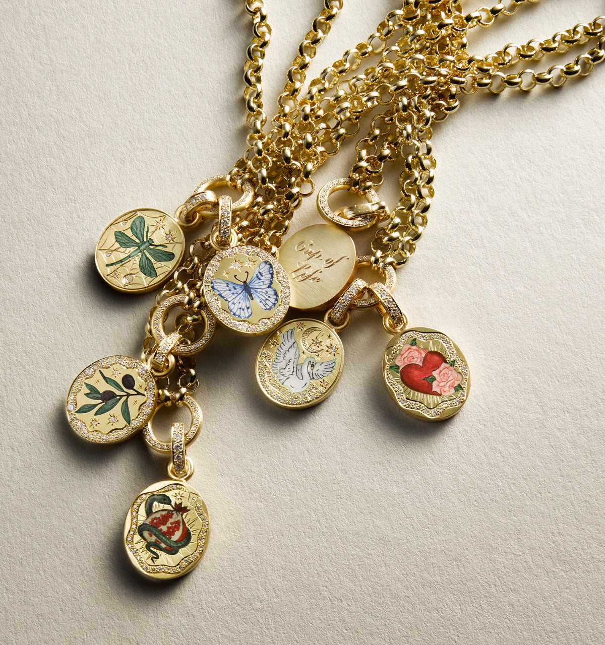 Gold pendant necklaces featuring enamel designs of butterflies, hearts, flowers, and leaves on a textured chain.