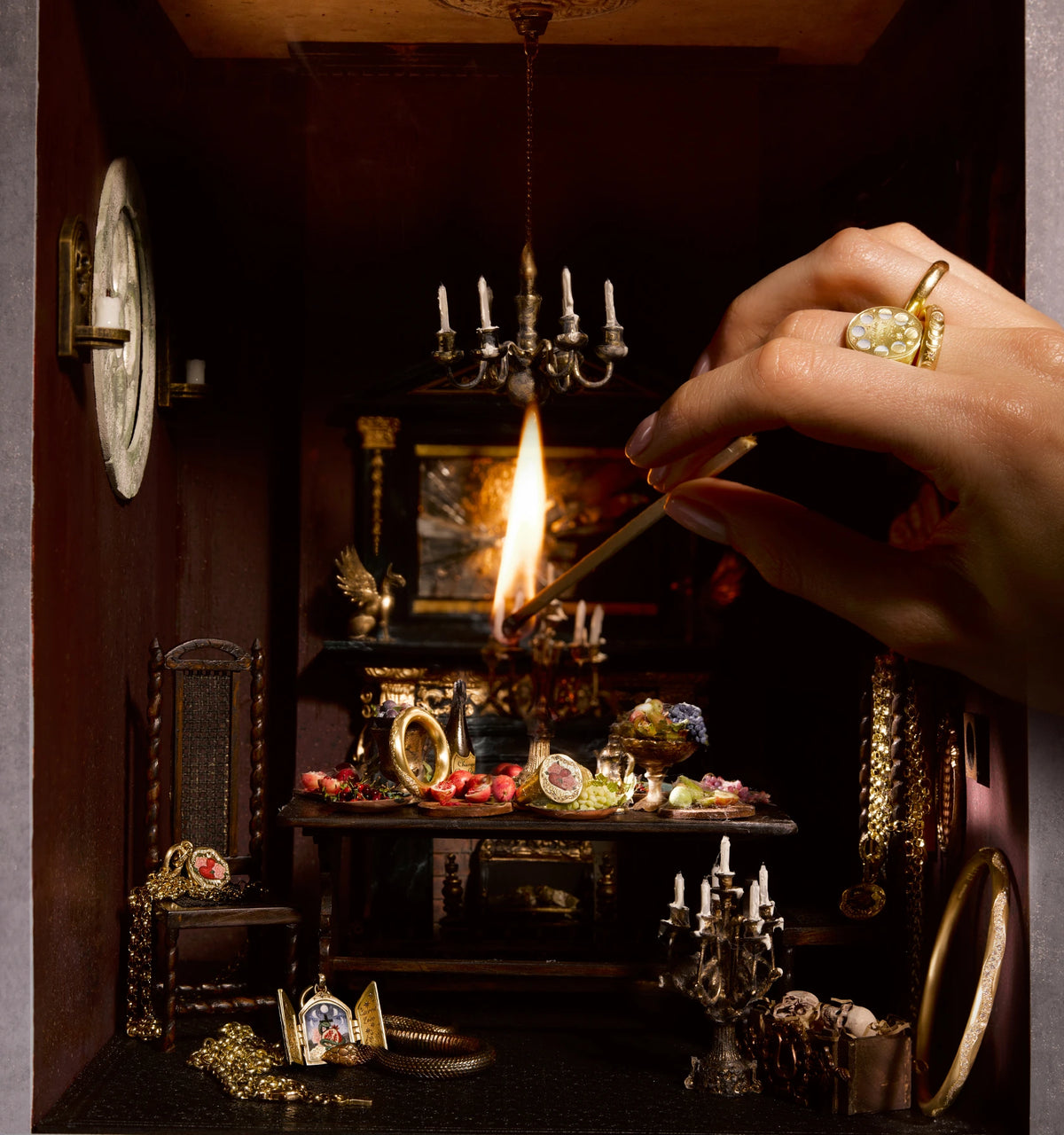 Woman wearing a gold ring and lighting a match in a vintage-themed room filled with various gold jewellery pieces.