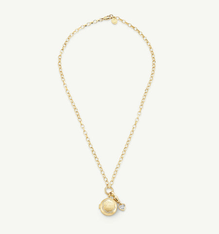 Gold necklace featuring a round pendant with engraved details and a small heart charm adorned with a diamond.