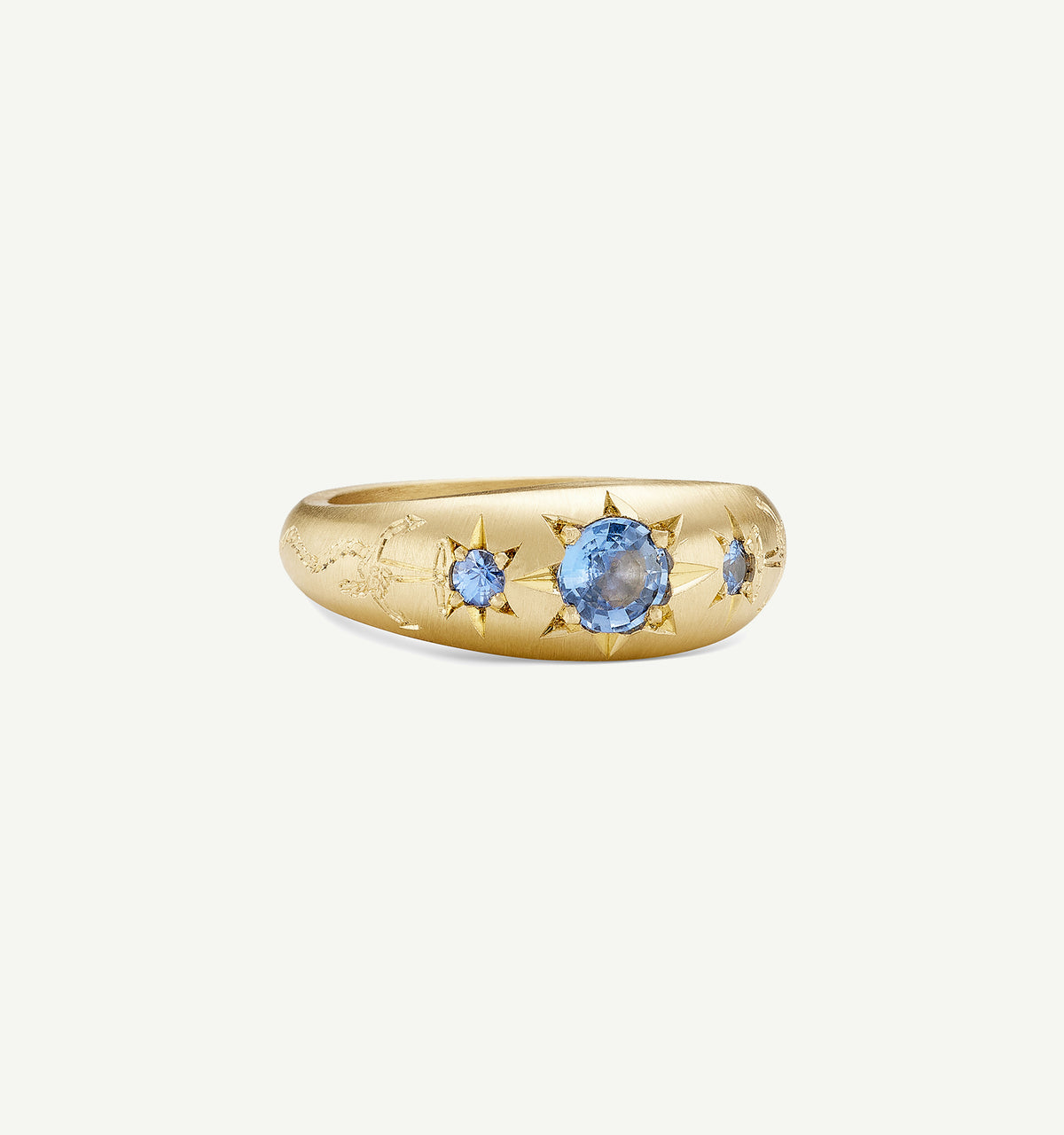 Gold ring featuring three blue sapphires with engraved star motifs.