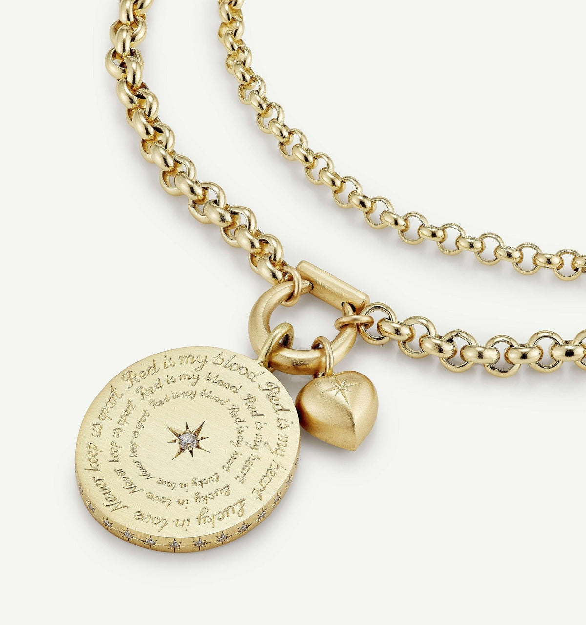 Gold necklace featuring a circular pendant with engraved text and a heart charm, accented by a small diamond.
